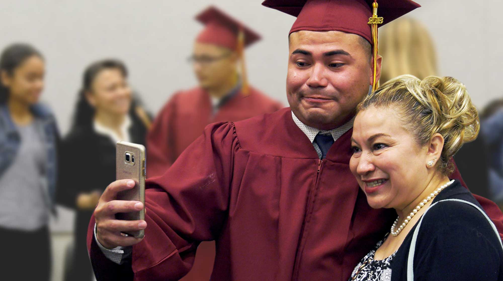 Emotional CCPA graduate looking at phone while standing near family member